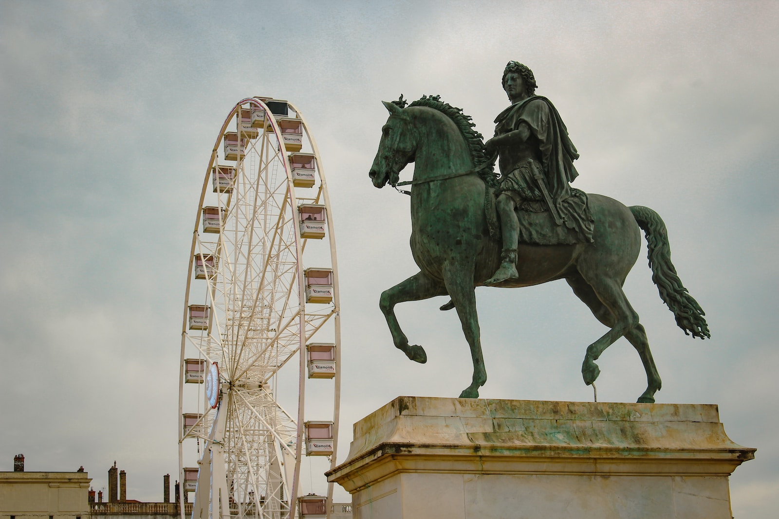 a statue of a man riding a horse next to a ferris wheel